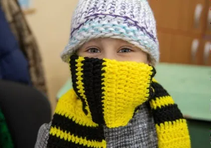 A child in a hand-knitted hat and scarf